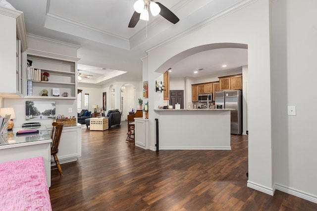 kitchen with ceiling fan, stainless steel appliances, ornamental molding, kitchen peninsula, and a raised ceiling