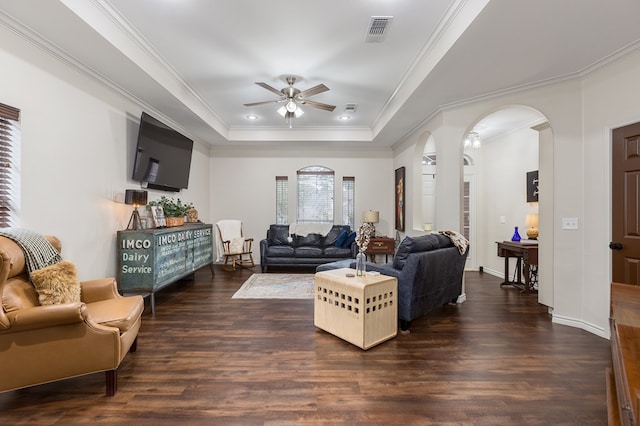 living room featuring dark hardwood / wood-style floors, ceiling fan, a tray ceiling, and crown molding