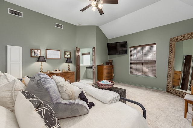 bedroom with ceiling fan, ensuite bathroom, vaulted ceiling, and light carpet