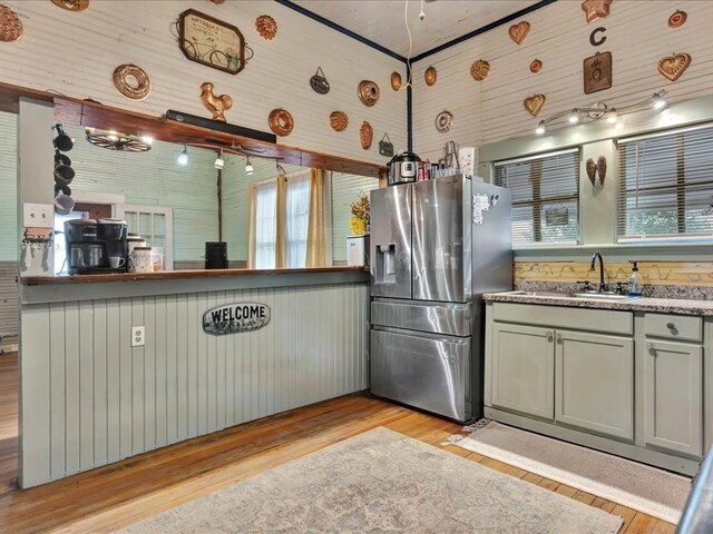 203 Chandler St, Diboll, TX 75941 - kitchen featuring stainless steel refrigerator with ice dispenser, light wood finished floors, gray cabinetry, and wooden walls
