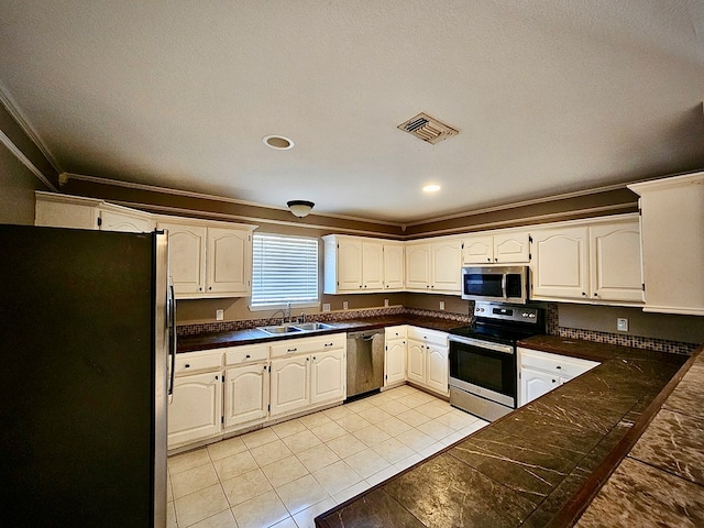 kitchen featuring stainless steel appliances, white cabinetry, crown molding, and light tile patterned flooring