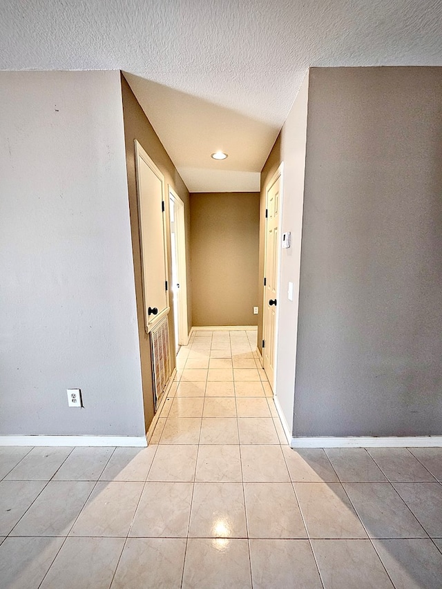 hall featuring light tile patterned flooring and a textured ceiling