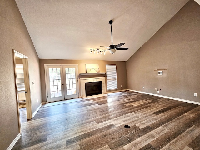 unfurnished living room with wood-type flooring, high vaulted ceiling, ceiling fan, and a tiled fireplace