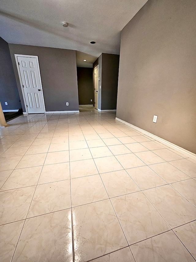 tiled empty room featuring a textured ceiling