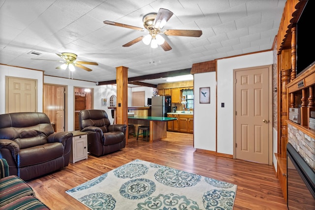 living room featuring light hardwood / wood-style flooring, ceiling fan, and a stone fireplace