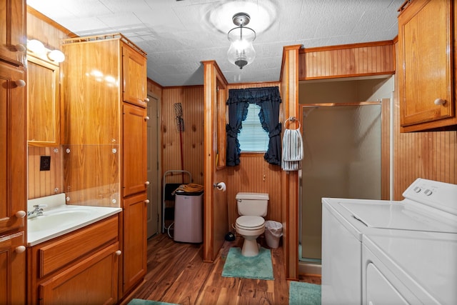 bathroom featuring wood walls, washer and clothes dryer, vanity, and hardwood / wood-style floors