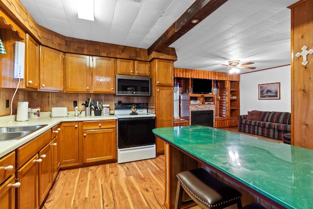 kitchen with beam ceiling, electric range, sink, ceiling fan, and light hardwood / wood-style floors