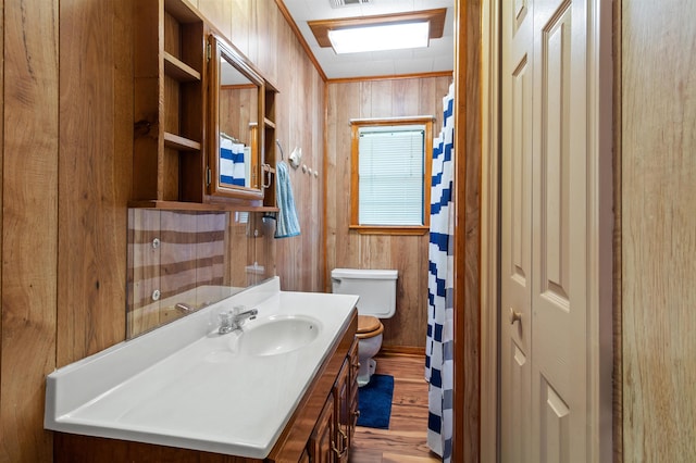 bathroom with vanity, wooden walls, crown molding, hardwood / wood-style floors, and toilet