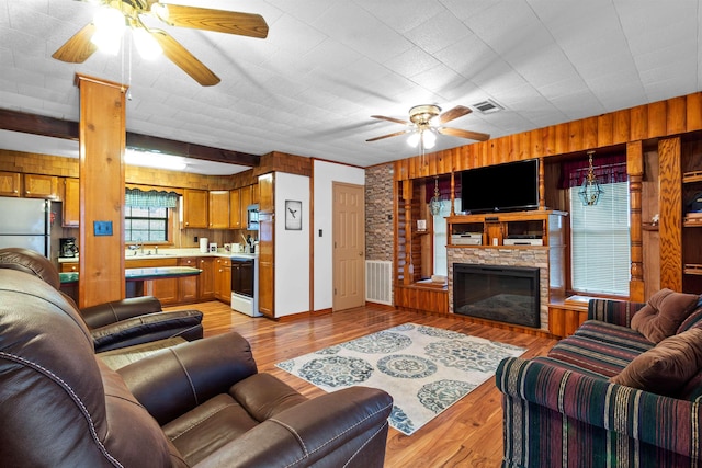 living room featuring a fireplace, light hardwood / wood-style floors, and ceiling fan