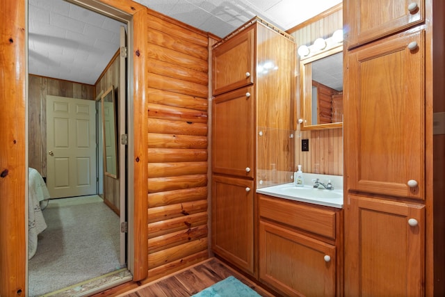 bathroom featuring log walls, hardwood / wood-style floors, and vanity