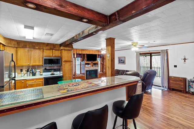 kitchen with light hardwood / wood-style floors, tasteful backsplash, beam ceiling, a kitchen bar, and stainless steel appliances