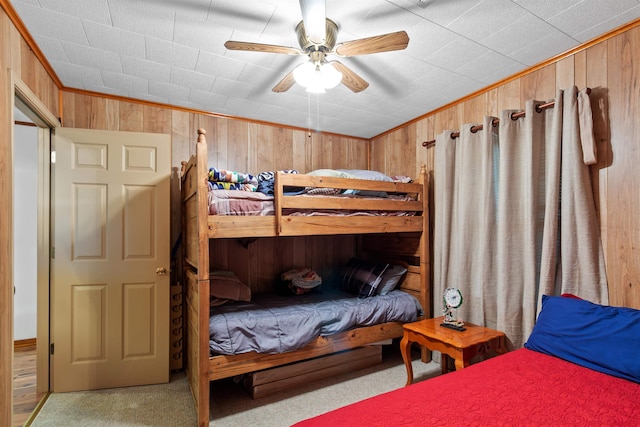 bedroom featuring light colored carpet, ceiling fan, ornamental molding, and wood walls