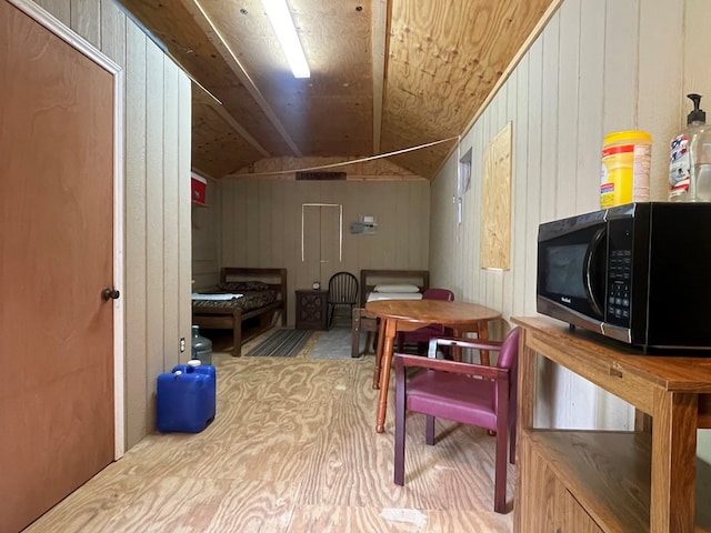 bonus room with wooden walls and vaulted ceiling