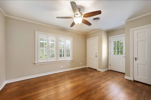 unfurnished room featuring wood finished floors, ornamental molding, baseboards, visible vents, and a ceiling fan