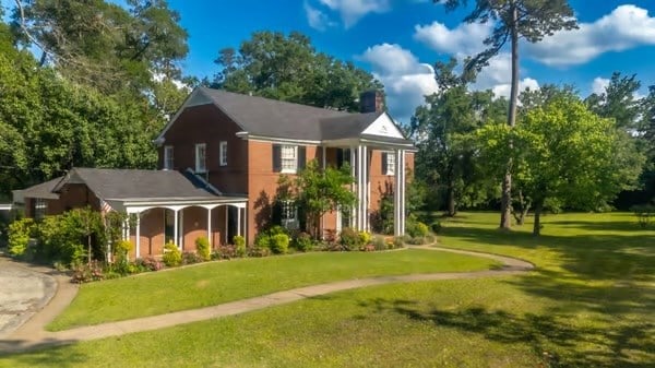 view of front of property with a porch, a chimney, and a front yard