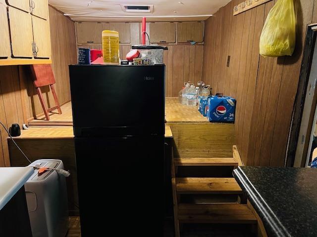 kitchen with wooden walls and black refrigerator