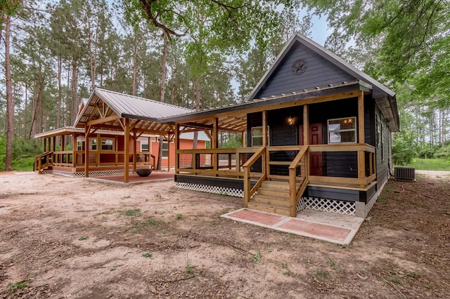 rear view of property with metal roof, a deck, and central AC