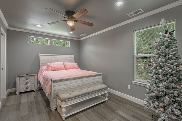 bedroom with wood finished floors, visible vents, crown molding, and baseboards