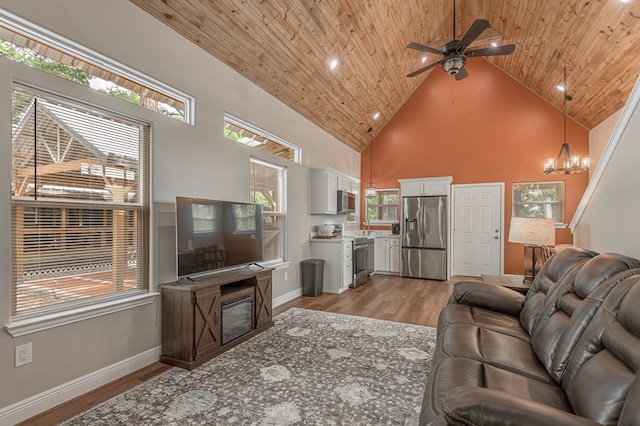 living area featuring wood ceiling, light wood-style flooring, high vaulted ceiling, and ceiling fan with notable chandelier