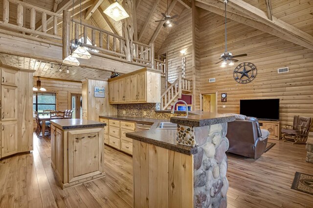 kitchen featuring sink, light brown cabinets, light hardwood / wood-style flooring, high vaulted ceiling, and kitchen peninsula