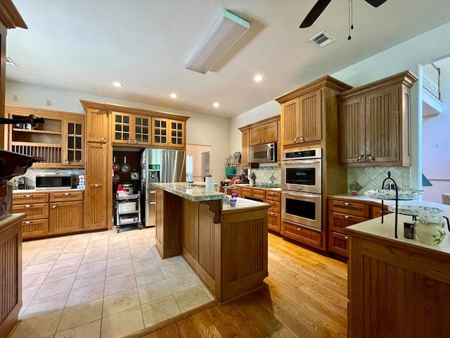 kitchen with backsplash, a breakfast bar, stainless steel appliances, light hardwood / wood-style flooring, and a kitchen island