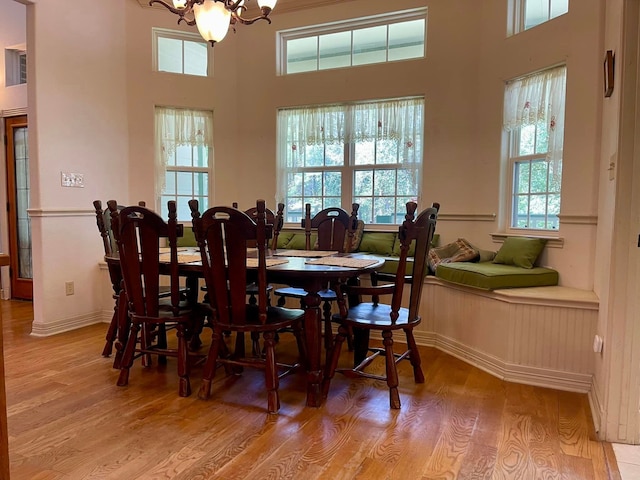 dining area featuring a wealth of natural light, light hardwood / wood-style flooring, a towering ceiling, and a chandelier