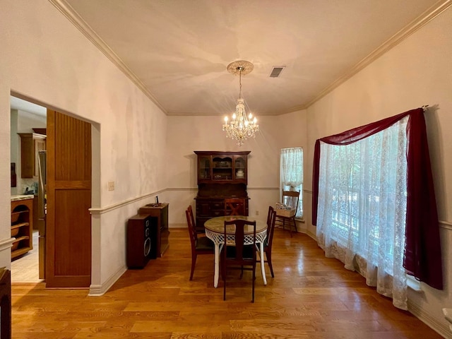 dining space featuring an inviting chandelier, wood-type flooring, and ornamental molding