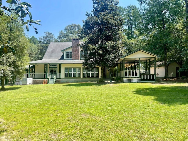 back of property with a lawn, cooling unit, and covered porch