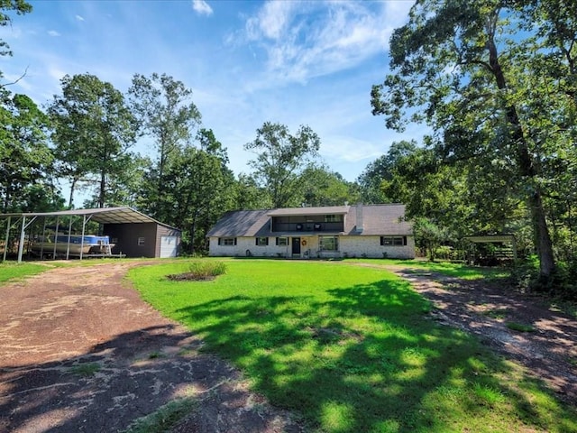 view of front of property featuring dirt driveway, a front lawn, and a detached carport