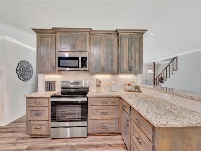 kitchen with decorative backsplash, appliances with stainless steel finishes, a peninsula, light stone countertops, and light wood-style floors