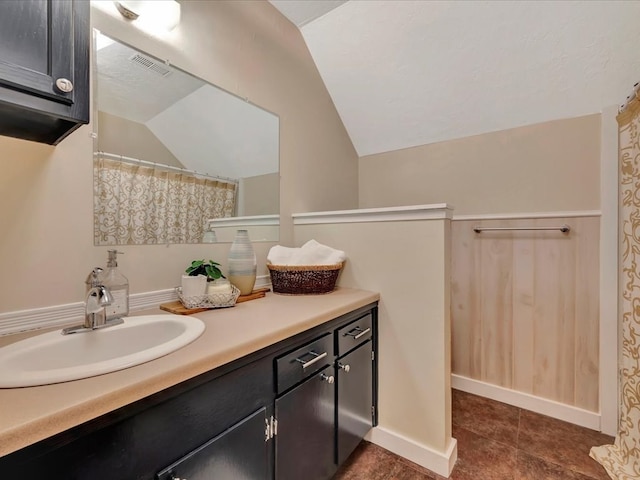 full bath with vaulted ceiling, vanity, and baseboards