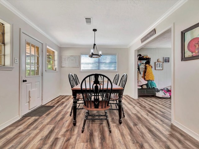 dining room featuring ornamental molding, wood finished floors, visible vents, and a notable chandelier