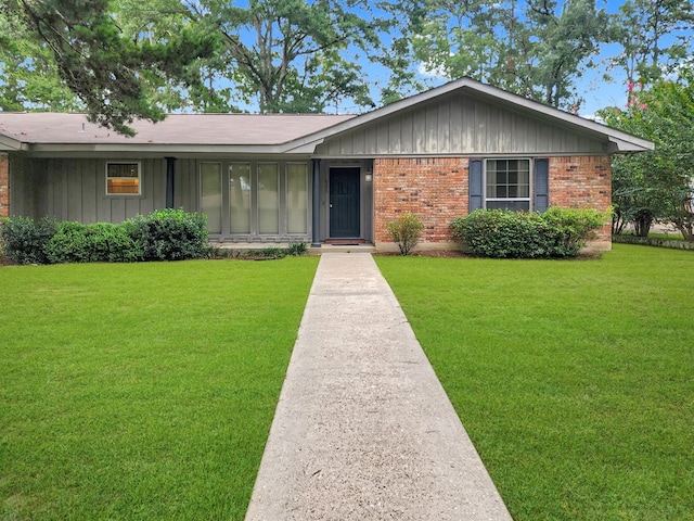 906 Richardson Dr, Jasper, TX 75951 - single story home with board and batten siding, a front yard, and brick siding
