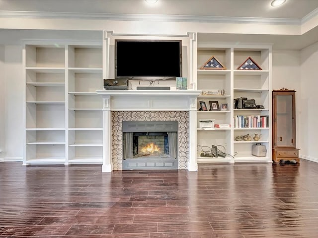 living room featuring a fireplace, dark hardwood / wood-style flooring, built in shelves, and ornamental molding