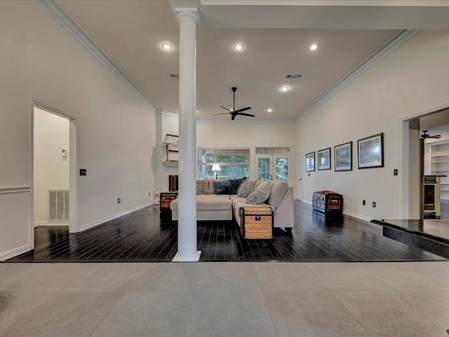 living room featuring decorative columns, crown molding, and wood-type flooring