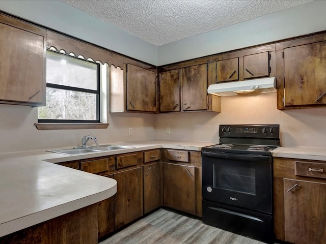 kitchen with black / electric stove, a sink, light countertops, under cabinet range hood, and a textured ceiling