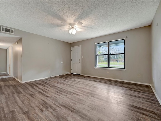 spare room with wood finished floors, baseboards, visible vents, ceiling fan, and a textured ceiling