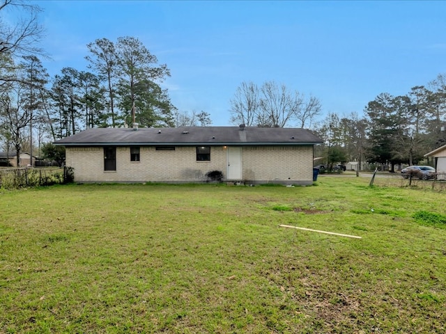 back of house featuring brick siding, a yard, and fence