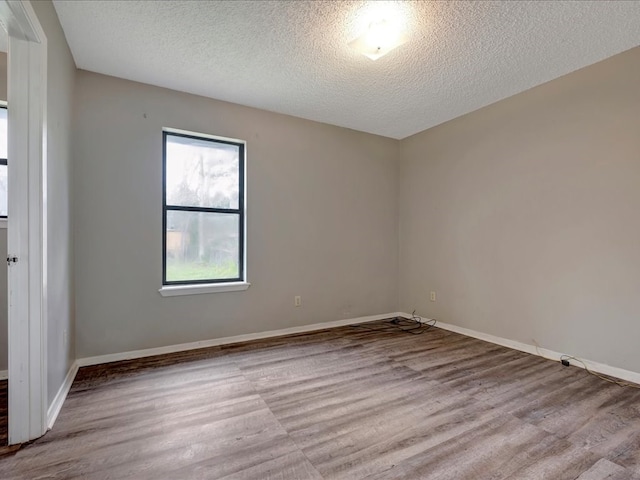 spare room featuring a textured ceiling, baseboards, and wood finished floors