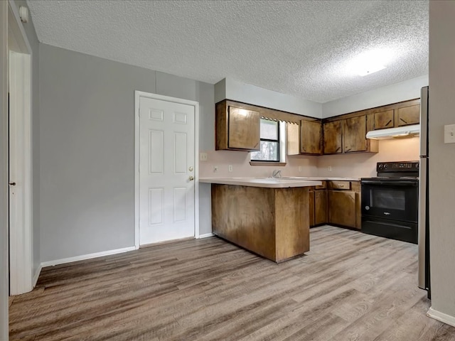 kitchen featuring under cabinet range hood, light countertops, a peninsula, light wood-style floors, and black / electric stove