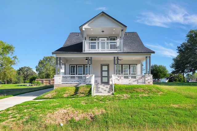 view of front of property featuring covered porch, a balcony, a front lawn, and ceiling fan