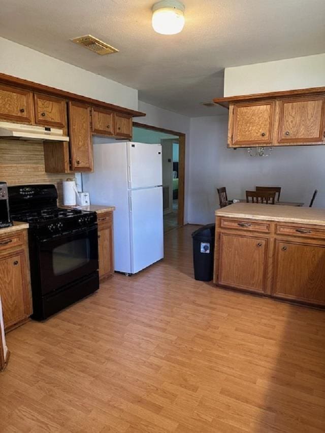 kitchen with white refrigerator, light hardwood / wood-style floors, and black range with gas cooktop