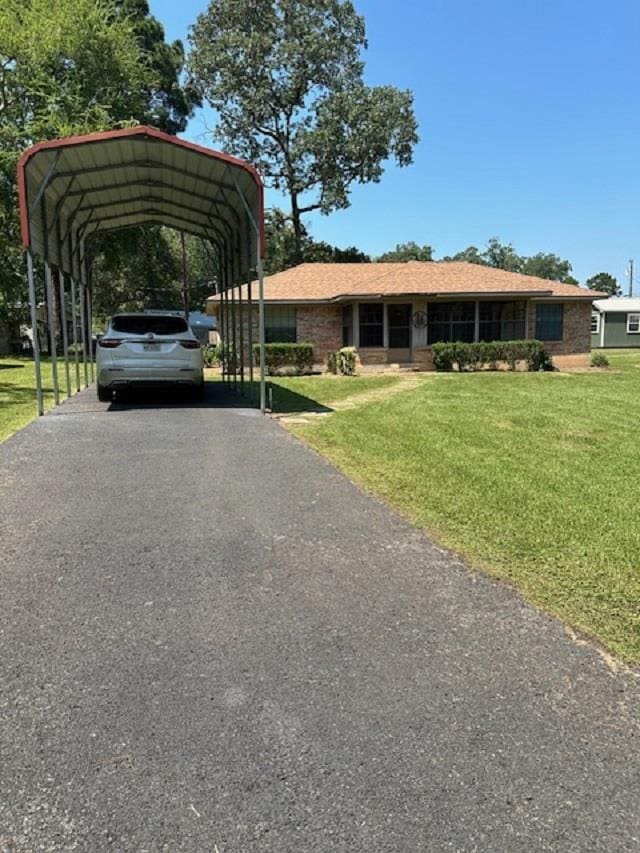 view of vehicle parking with a lawn and a carport