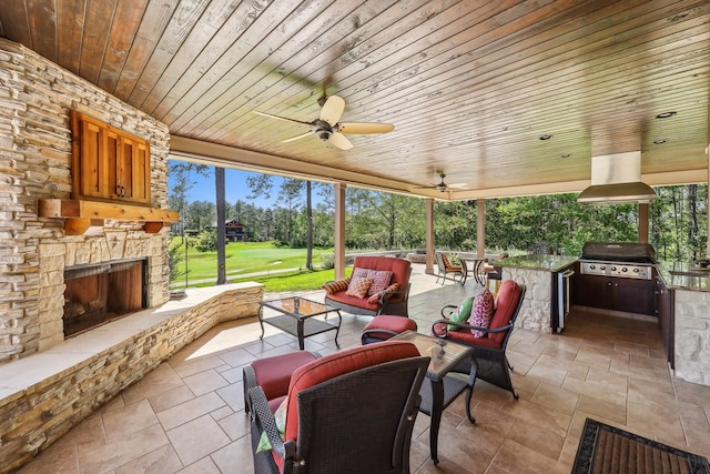 225 Mcgregor Dr, Brookeland, TX 75931 - view of patio / terrace with an outdoor living space with a fireplace, a grill, a ceiling fan, exterior kitchen, and view of golf course