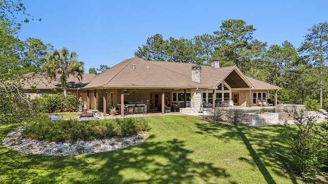 225 Mcgregor Dr, Brookeland, TX 75931 - back of property featuring a tiled roof, stucco siding, a chimney, a yard, and a patio area