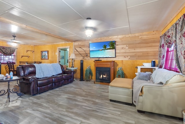 living room with hardwood / wood-style floors, ceiling fan, and wooden walls