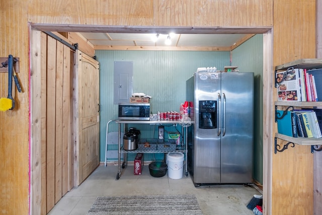 kitchen with appliances with stainless steel finishes, a barn door, electric panel, and wood walls