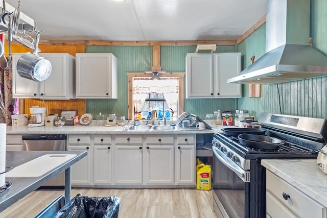 kitchen with white cabinetry, sink, wall chimney exhaust hood, light hardwood / wood-style floors, and appliances with stainless steel finishes