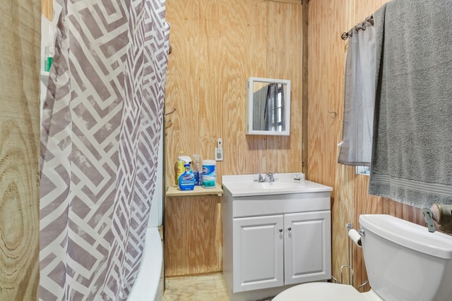 bathroom featuring wood walls, vanity, and toilet