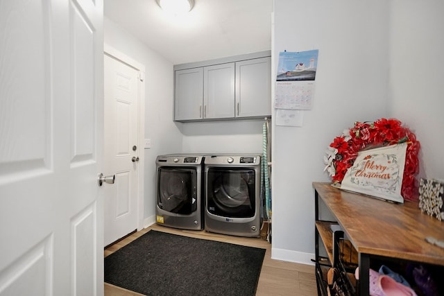 laundry room featuring cabinets, light hardwood / wood-style floors, and washing machine and dryer